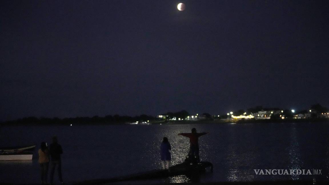 $!La gente se reúne para ver la luna parcialmente eclipsada que se asienta sobre el río Paraguay en Asunción, Paraguay. AP/Jorge Saenz