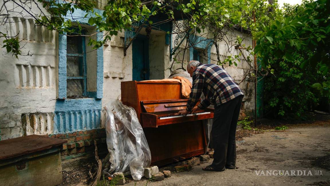 $!Anatolii Virko toca el piano ante una casa probablemente dañada por un ataque ruso en el poblado de Velyka Kostromka, Ucrania, el jueves 19 de mayo de 2022.