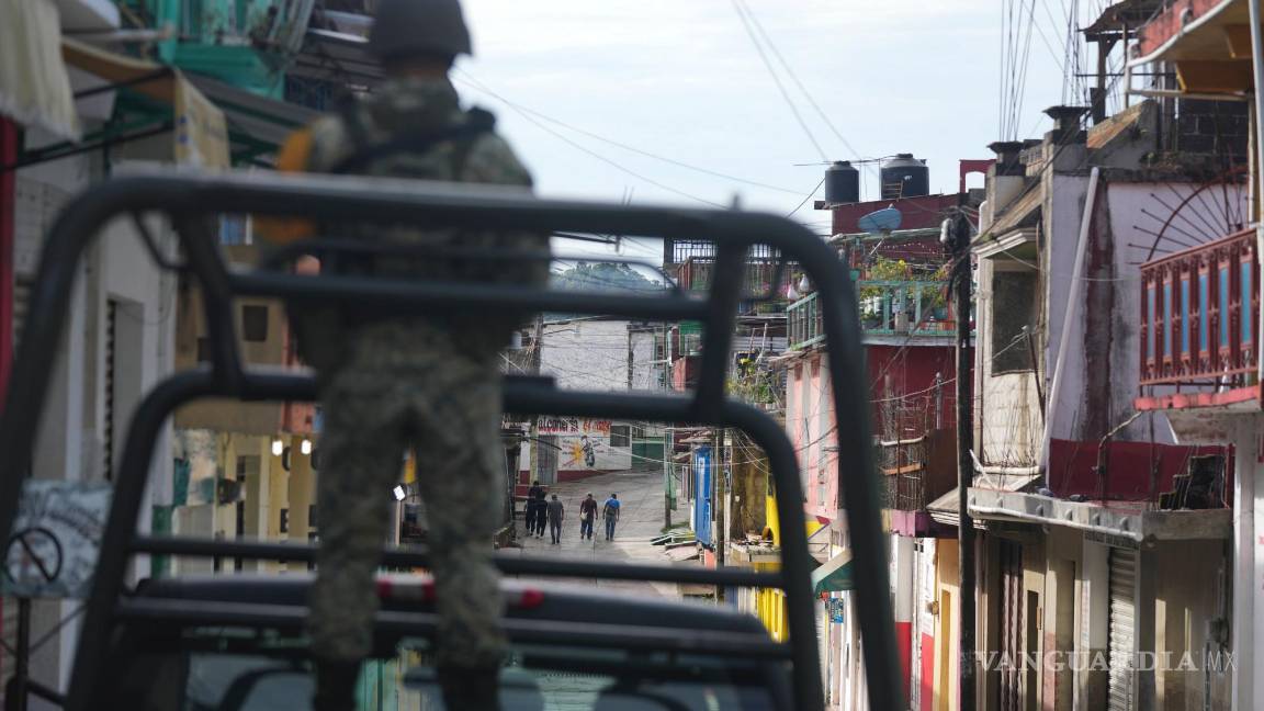 $!Agricultores pasan junto a tiendas cerradas para trabajar en el campo bajo la vigilancia de soldados en Tila, en el estado de Chiapas, México.