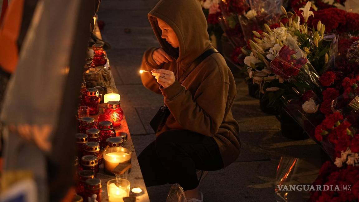 $!Una joven se persigna mientras enciende una vela en un monumento para los miembros del grupo militar del Grupo Wagner muertos en un accidente aéreo.