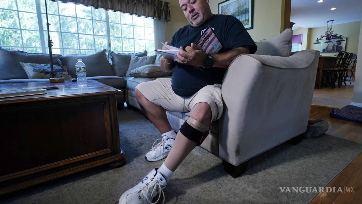 $!Will Jimeno, un ex agente de policía de la Autoridad Portuaria que fue rescatado de entre los escombros del World Trader Center el 11S, lee el libro ilustrado para niños que escribió Immigrant, American, Survivor (“Inmigrante, Estadounidense, Sobreviviente”) contando su experiencia, durante una entrevista en su casa en Chester, Nueva Jersey, el 2 de agosto de 2021. Herido en el 11S, Jimeno usa una media de compresión y un brazalete en su pierna izquierda. AP/Richard Drew