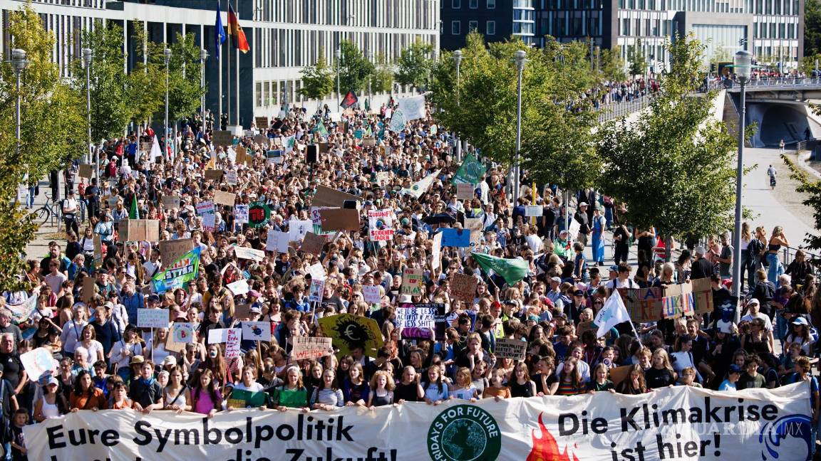 $!Los manifestantes sostienen una pancarta que dice “Su política simbólica nos está costando nuestro futuro” (izq.) y “La crisis climática está aquí” (der.) en Berlín.