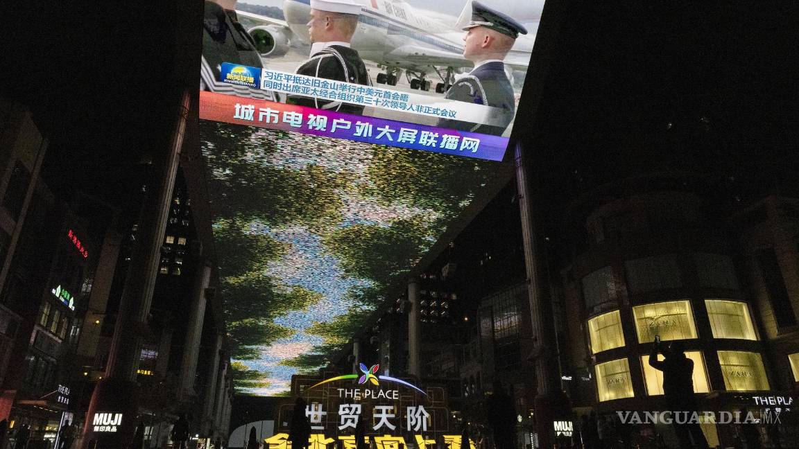 $!Un hombre (d) toma una fotografía de una gran pantalla que muestra la llegada del presidente chino Xi Jinping a Estados Unidos, en un centro comercial de Beijing.