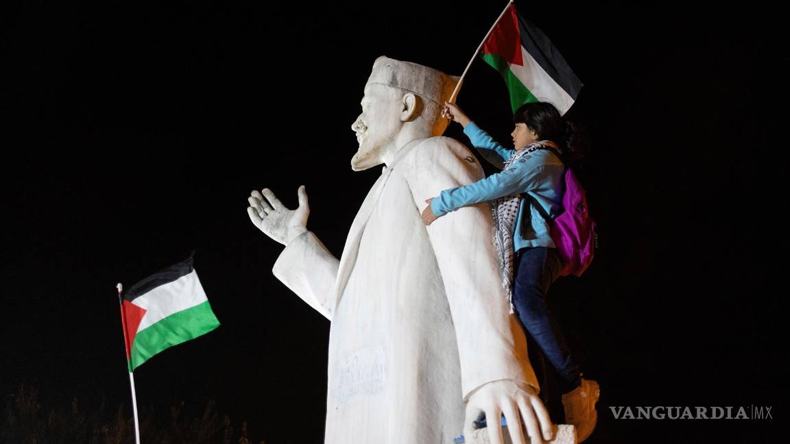 $!Un manifestante sobre una estatua iza la bandera palestina mientras los palestinos que viven en Grecia piden por “Palestina libre” en Salónica, Grecia.