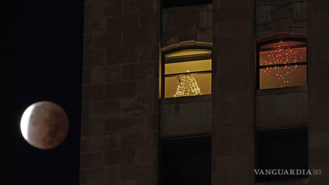 $!La sombra de la tierra cubre la luna llena durante un eclipse lunar parcial cuando se pone más allá de un edificio de apartamentos en el centro de Kansas City, Missouri. AP/Charlie Riedel