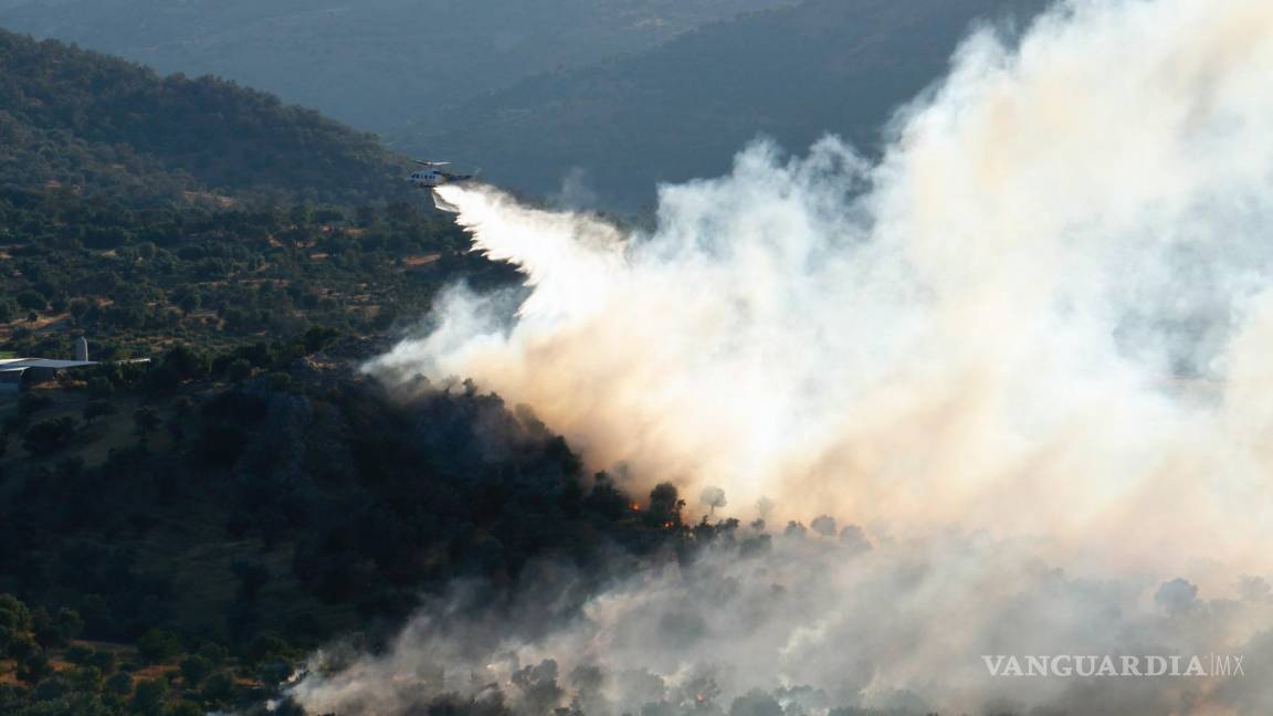 $!Un helicóptero de extinción de incendios arroja agua para extinguir el fuego en la aldea de Agia Galini en el municipio de Agios Vassilios, Rethimno, Grecia.