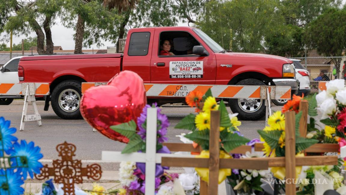 $!Un pasajero en una camioneta mira un sitio conmemorativo donde ocho migrantes murieron mientras esperaban en una parada de autobús en Brownsville, Texas.