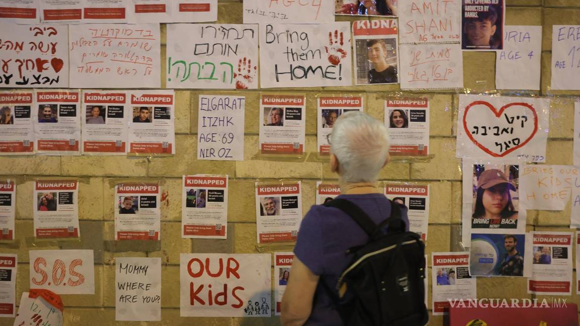 $!Una persona mira fotografías de rehenes retenidos por militantes de Hamas durante una protesta pidiendo al gobierno israelí que ayude a rescatarlos.
