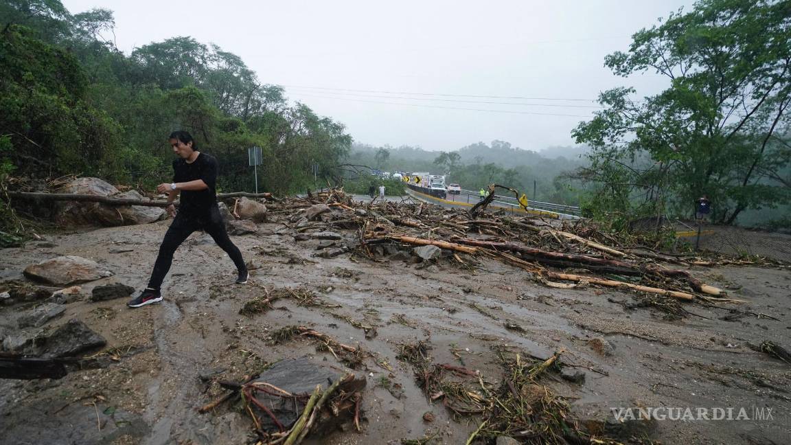 $!Un hombre cruza una carretera bloqueada por un deslizamiento de tierra provocado por el huracán Otis cerca de Acapulco, México.