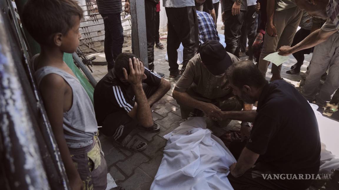 $!Dolientes se reúnen en torno a los cadáveres de los palestinos que murieron al intentar llegar a los camiones de ayuda que ingresan al norte de Gaza.