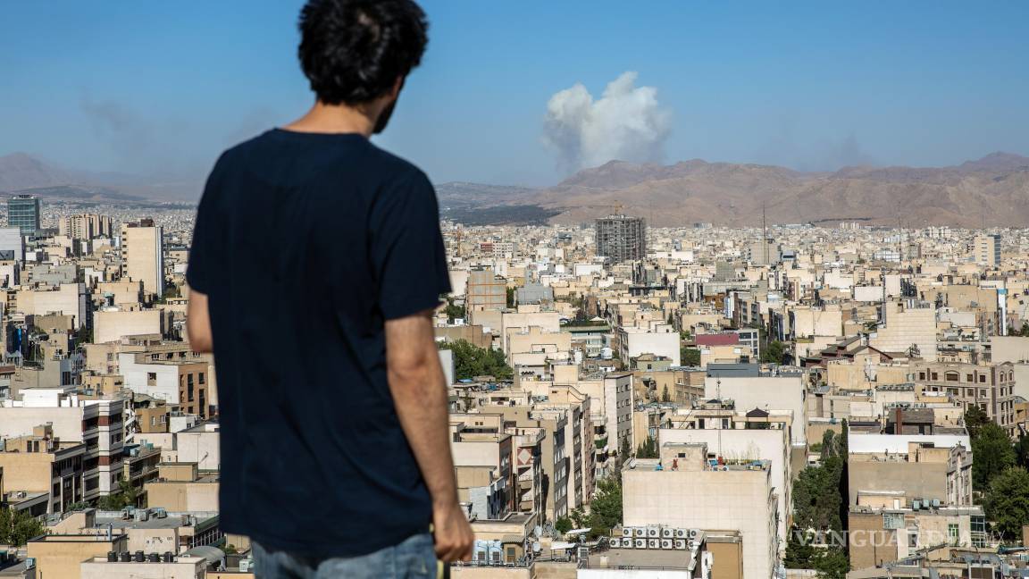 $!Un hombre en Teherán observa cómo se elevan columnas de humo durante un ataque aéreo israelí.