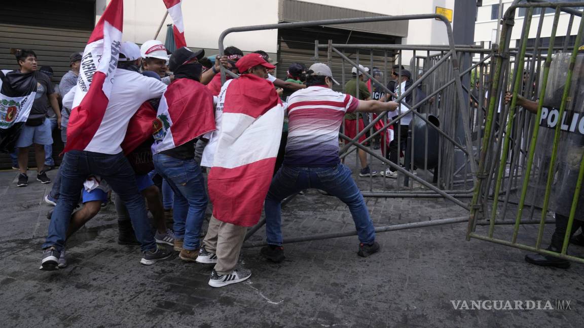 $!Manifestantes opositores que viajaron a la capital para marchar contra la presidenta peruana Dina Boluarte derriban una barricada de la policía.