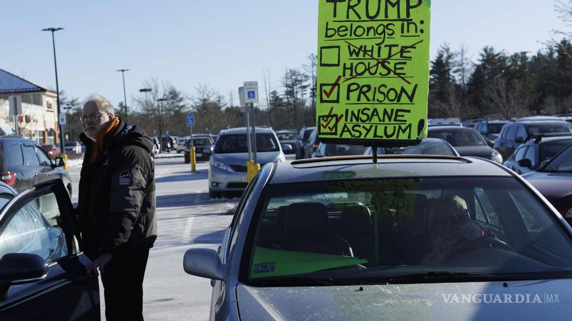 $!Una mujer sostiene un cartel en el techo de su vehículo en protesta contra el expresidente Donald Trump afuera en New Hampshire.