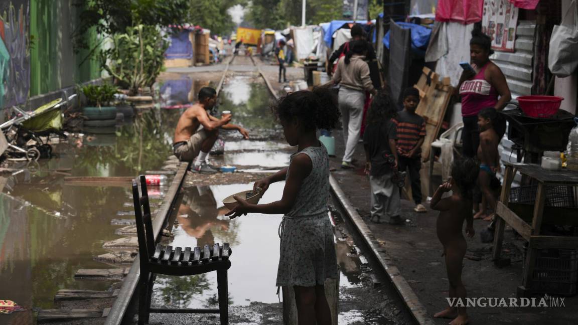 $!Un joven migrante lava un plato después de un aguacero en un campamento instalado a lo largo de las vías del tren Vallejo en Ciudad de México.