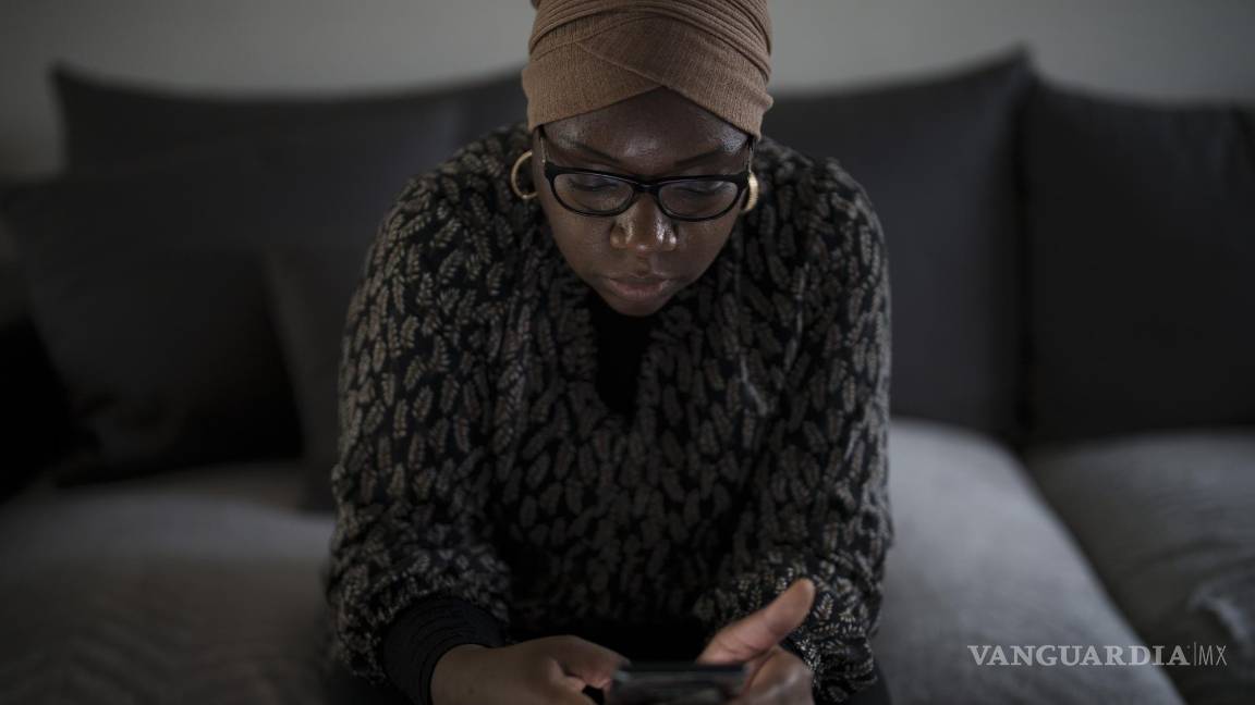 $!May Sow, cuyo sobrino Alassane Sow desapareció tras embarcar en un cayuco en Mauritania, mira su celular en su casa en Orleans, Francia.