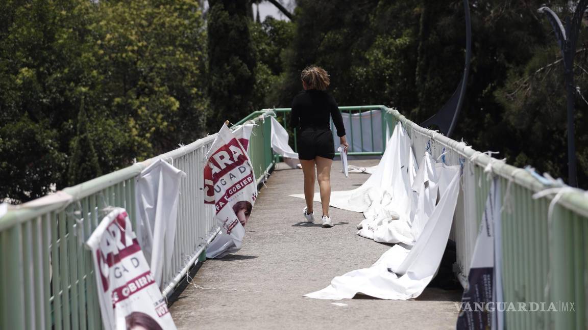 $!Un mujer camina junto a carteles de propaganda electoral en la Ciudad de México (México).