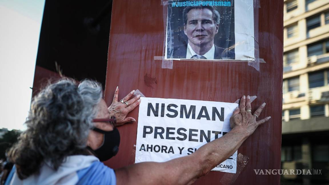 $!Fotografía del 18 de enero de 2021. Una mujer cuelga un cartel en un retrato del fiscal argentino Alberto Nisman, en un acto por el sexto aniversario de su muerte.