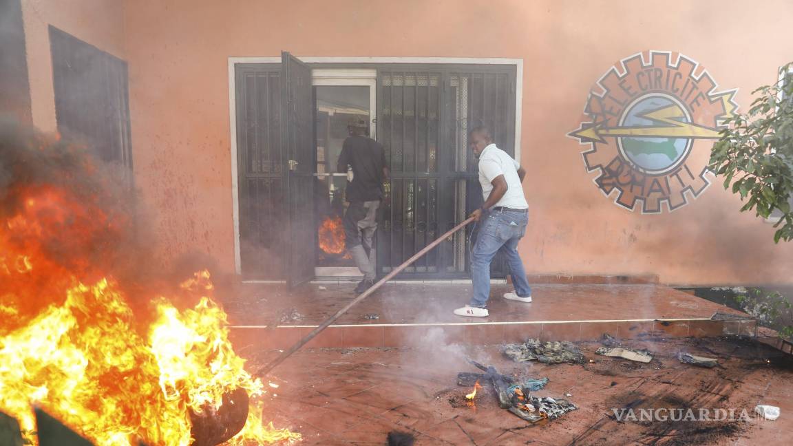$!Trabajadores apagan un incendio en una oficina de la empresa eléctrica del país durante una protesta para exigir la renuncia del primer ministro, Ariel Henry.