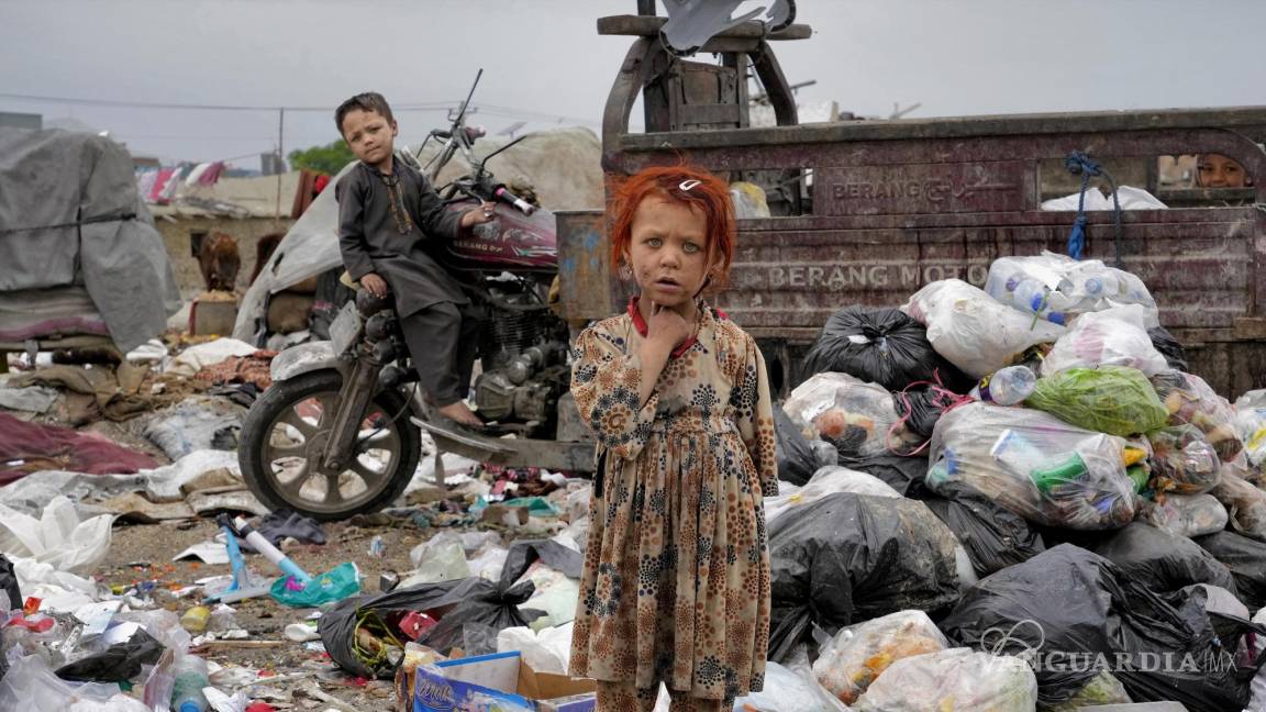 $!Dos niños afganos se paran en medio de montones de basura al lado de su casa, en Kabul, Afganistán.