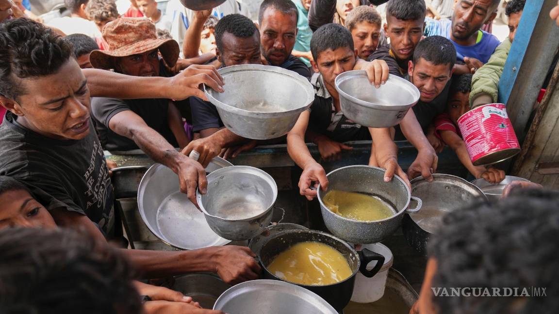 $!Palestinos tratan de conseguir comida cocinada de una cocina comunitaria en Jan Yunis, en el sur de la Franja de Gaza.