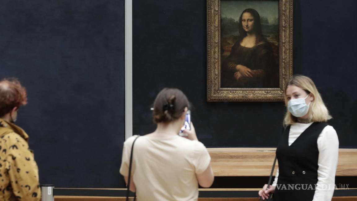$!Los visitantes posan frente a la Mona Lisa de Leonardo da Vinci en el museo del Louvre en París.