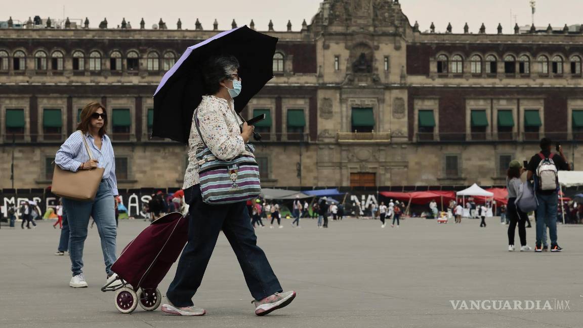 $!Una mujer camina con sombrilla para protegerse del sol en Ciudad de México.