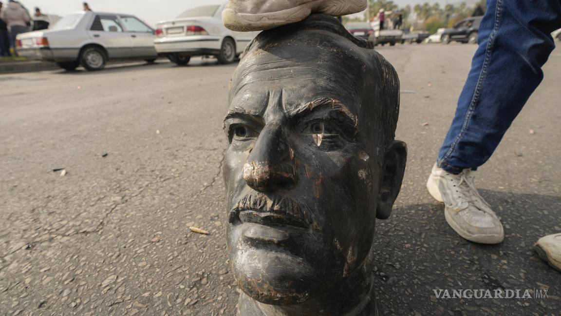 $!Un combatiente de oposición pone su pie sobre el busto del difunto presidente sirio Hafez Assad en Damasco, Siria.