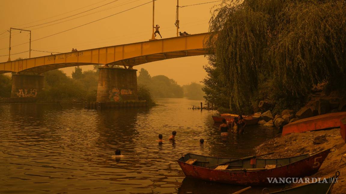 $!Varias personas nadan en el río Renaico bajo un cielo cubierto del humo causado por los incendios, en Renaico, Chile, el 4 de febrero de 2023.