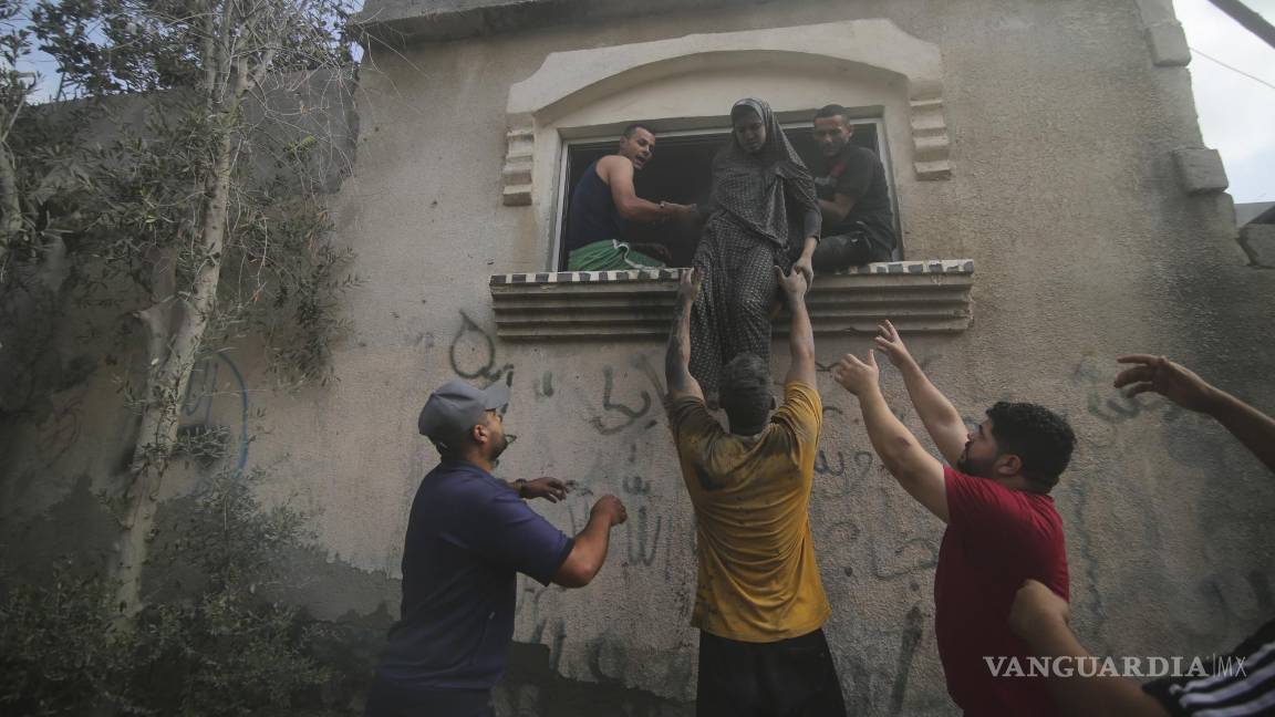 $!Palestinos desalojan un edificio alcanzado por un bombardeo aéreo israelí sobre la Franja de Gaza, en Rafah, el 22 de octubre de 2023.