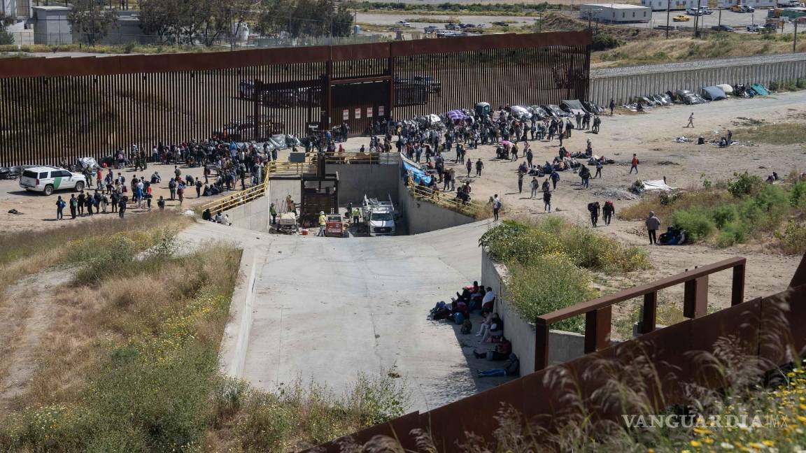 $!Migrantes esperan a las autoridades americanas, tras pasar el muro fronterizo que divide a México-Estados Unidos en la frontera con Tijuana, Baja California.