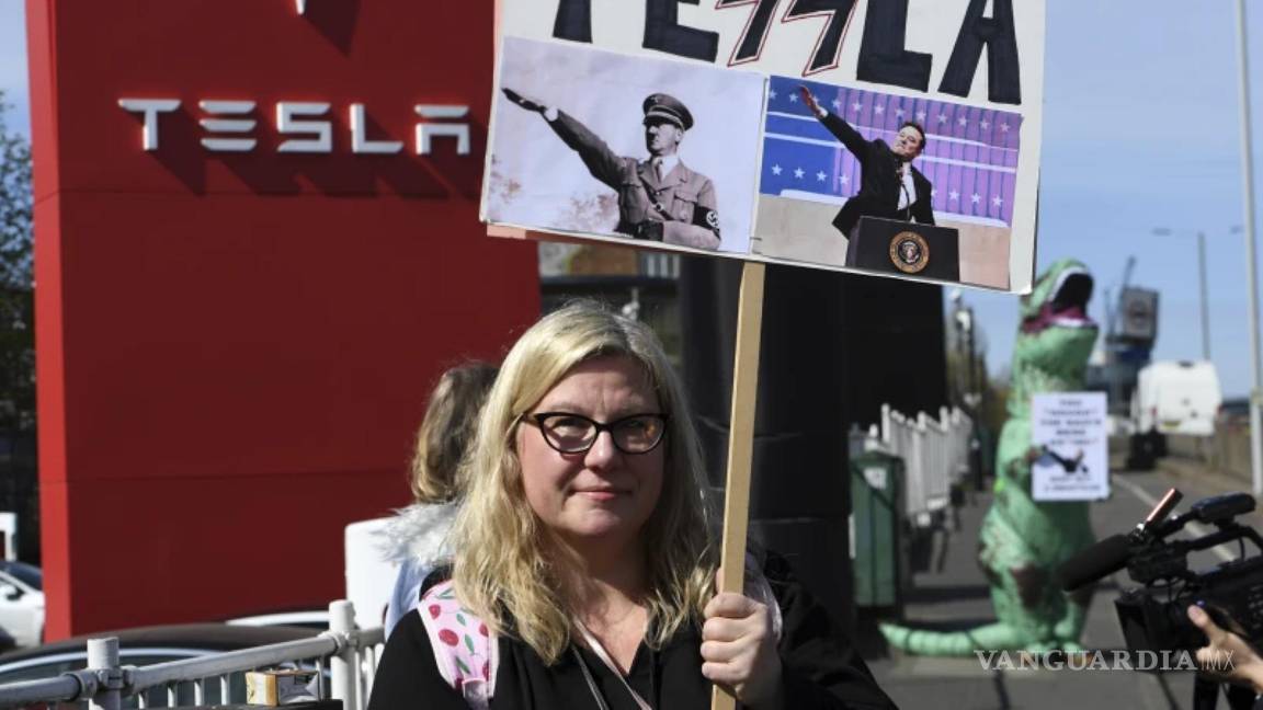 $!Una manifestante sostiene una pancarta mientras participa en el Día de Acción Global para Derribar Tesla cerca de un concesionario de Tesla en Londres.
