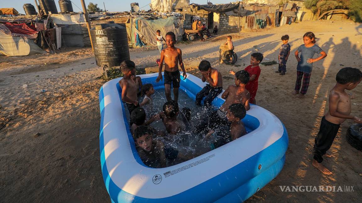 $!Niños refugiados palestinos se refrescan en una piscina inflable en un barrio marginal en las afueras del campo de refugiados de Khan Younis, Franja de Gaza.