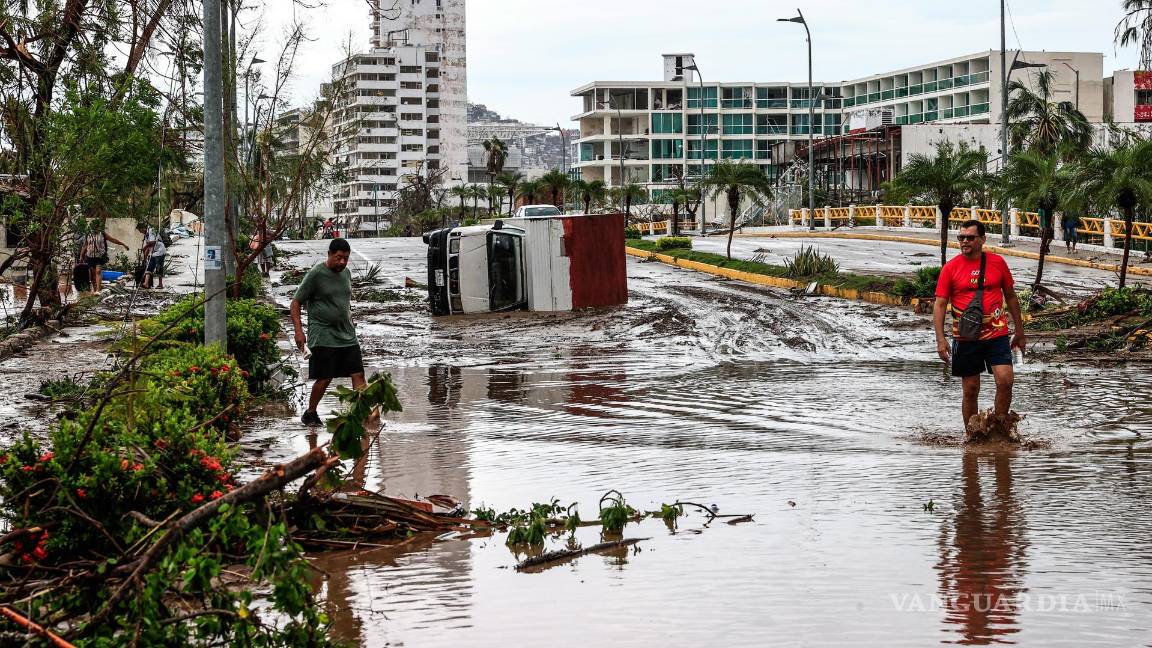 $!Vecinos caminan entre los escombros en una calle inundada por el huracán Otis en el balneario de Acapulco, en el estado de Guerrero, México.