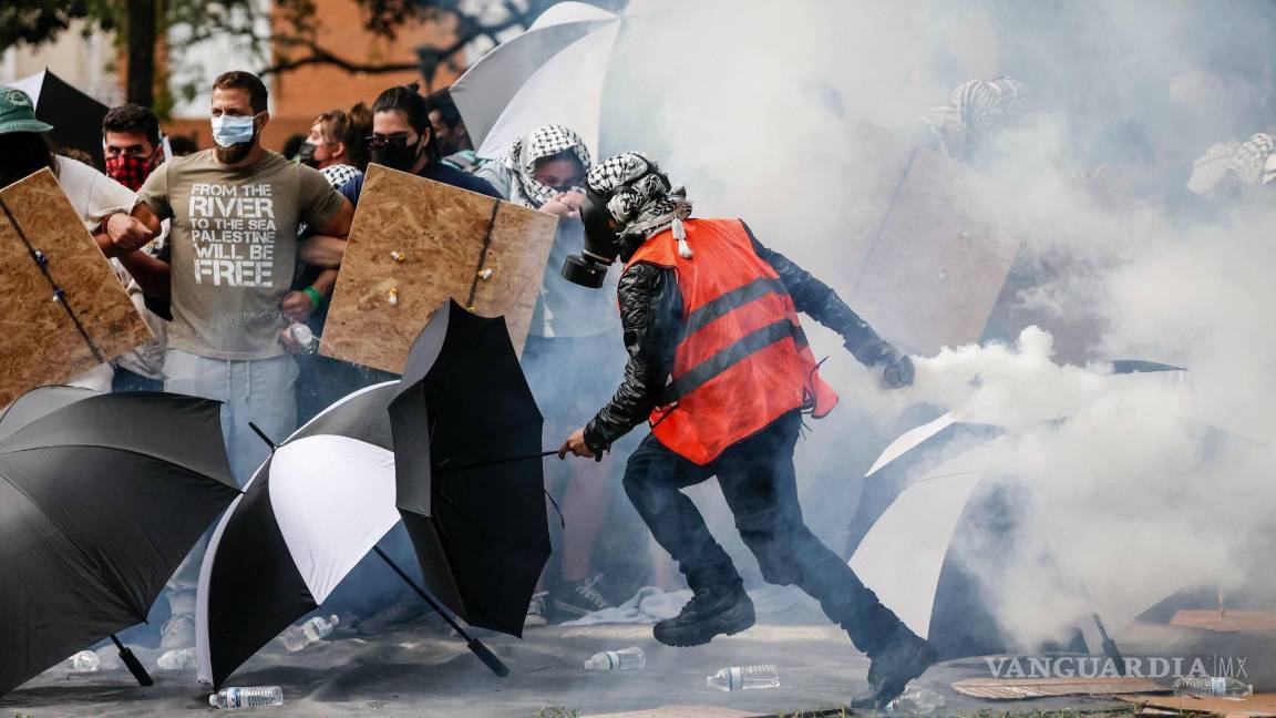 $!Un manifestante pro palestino devuelve un bote de gas lacrimógeno a la policía después de que cayó contra manifestantes en la Universidad del Sur de Florida.