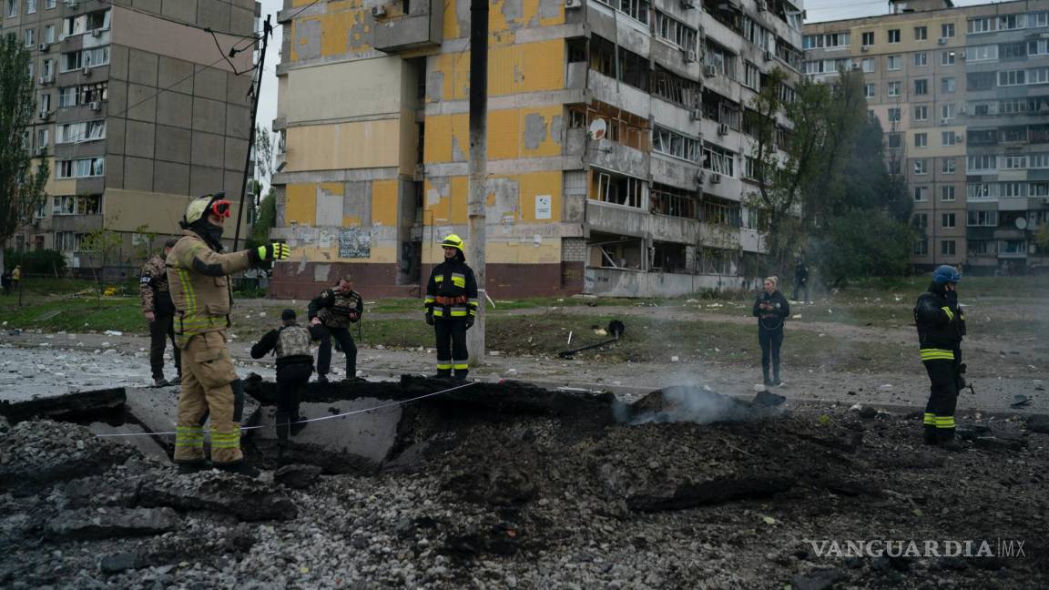 $!Bomberos y policías trabajan en un sitio donde una explosión creó un cráter en la calle después de un ataque ruso en Dnipro, Ucrania.