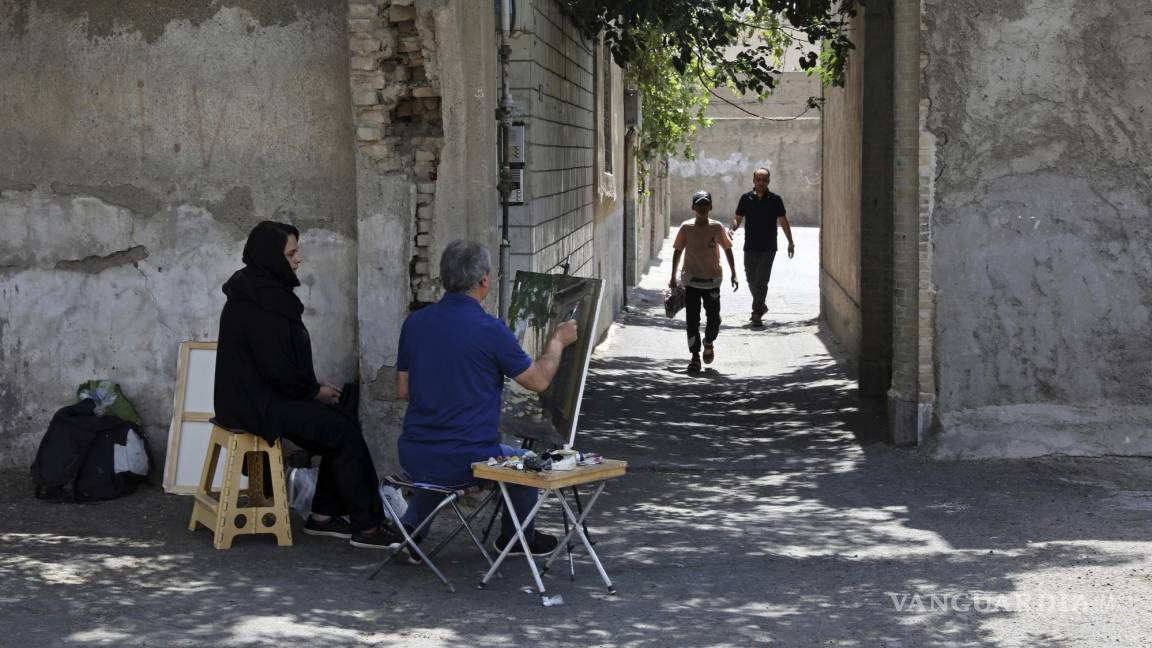 $!El pintor Hassan Naderali, junto a su asistente Minoo Amini, pinta un edificio antiguo en el barrio histórico de Oudlajan, en Teherán, Irán.