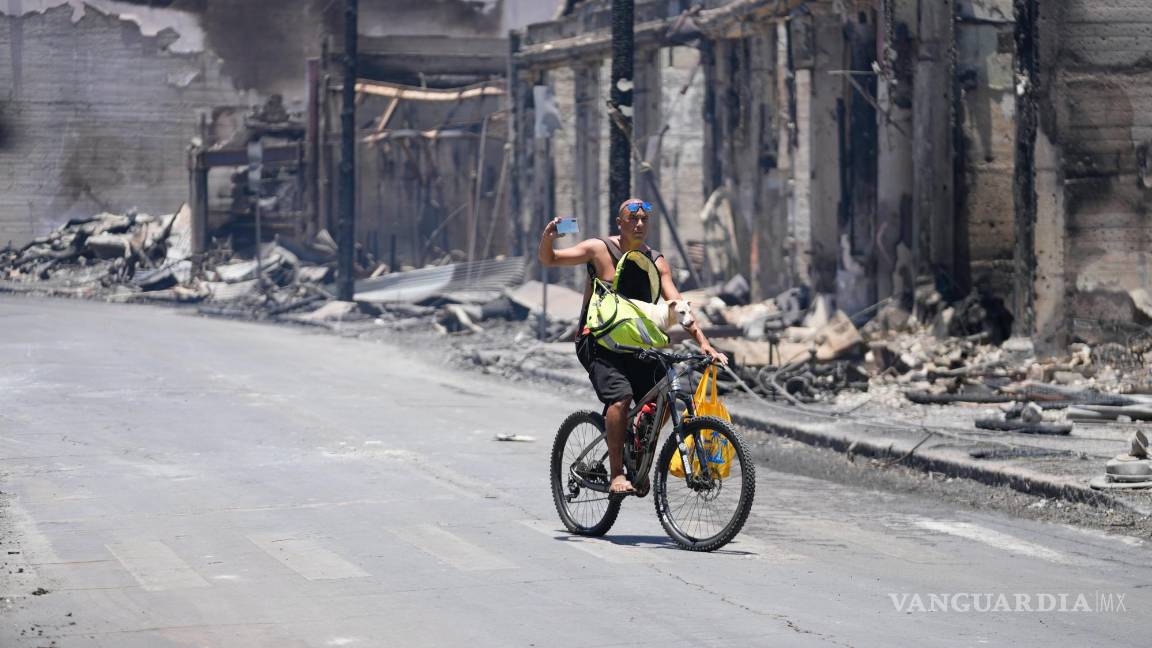 $!Un hombre y un perro pasean por Main Street más allá de los daños causados por un incendio forestal en Lahaina, Hawái.
