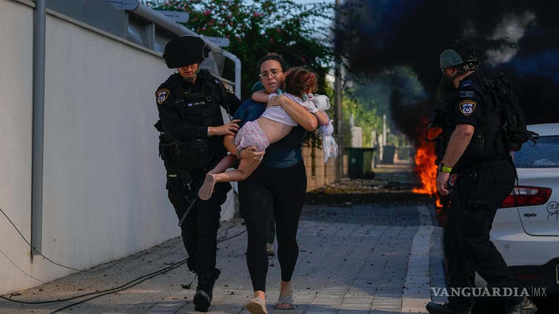 $!Policías israelíes evacuan a una mujer y a un niño de un lugar alcanzado por un cohete disparado desde Gaza, en Ashkelon, Israel, el 7 de octubre de 2023.