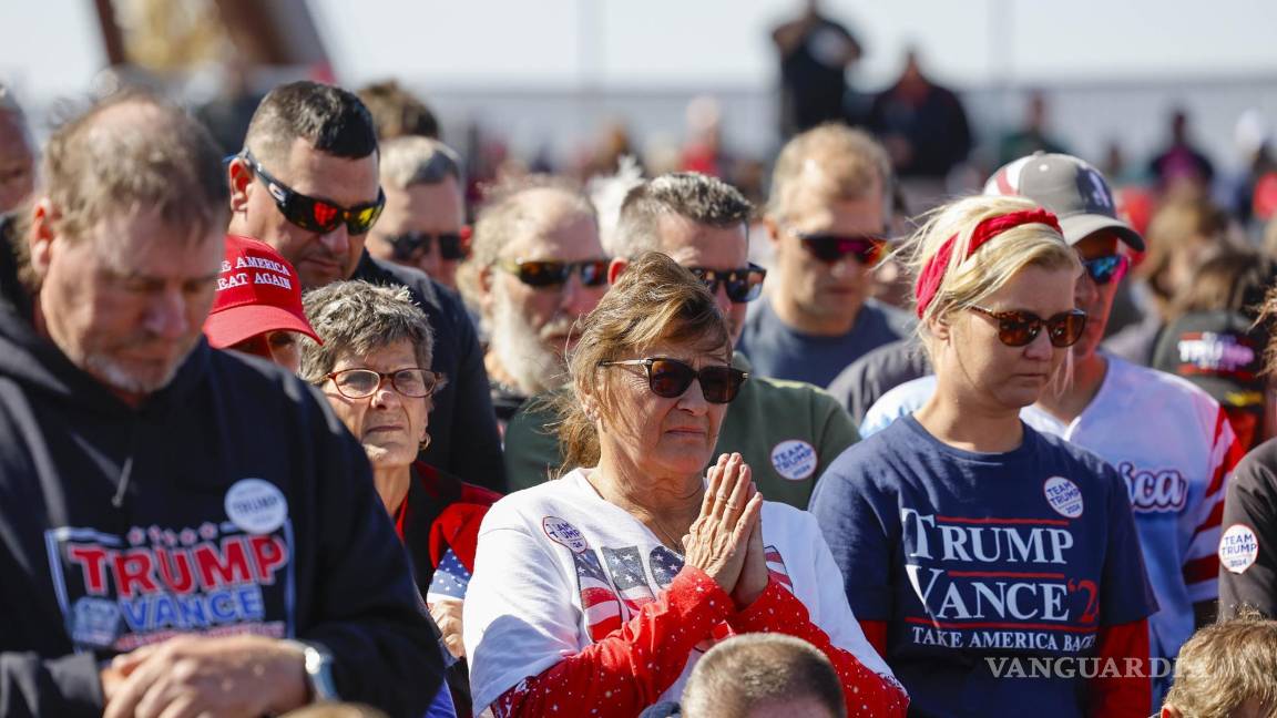 $!Partidarios rezan antes de que Donald Trump hable durante un mitin de campaña en el aeropuerto del condado de Dodge en Juneau, Wisconsin.