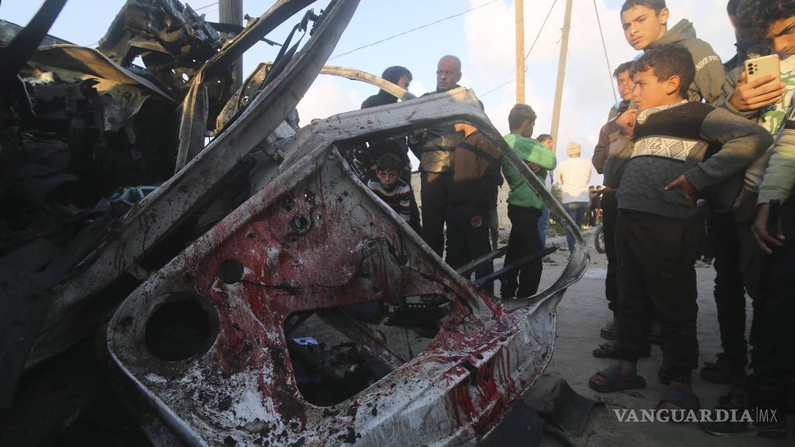 $!Menores palestinos observan un auto policial de Hamas destruido por un ataque israelí, en Rafah.