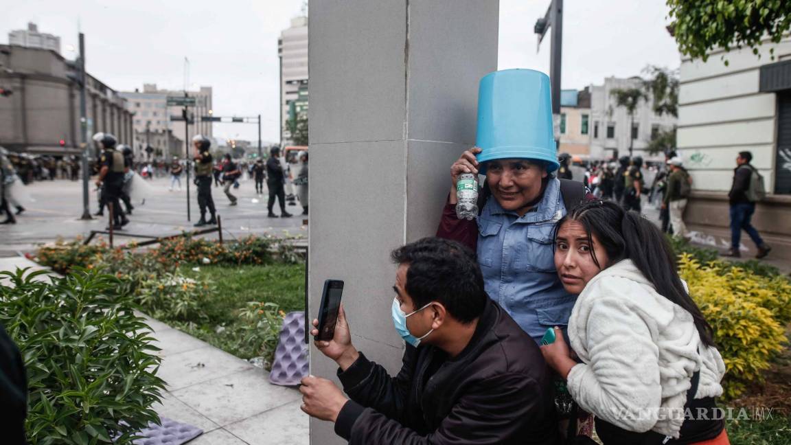 $!Un grupo de personas se resguarda durante los enfrentamientos entre manifestantes y la Policía a las afueras de la Prefectura de Lima.