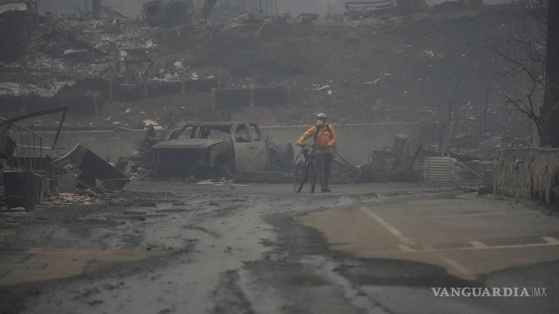 $!Una persona anda en bicicleta por una zona quemada mientras el incendio de Palisades arrasa un vecindario en el vecindario Pacific Palisades de Los Ángeles.