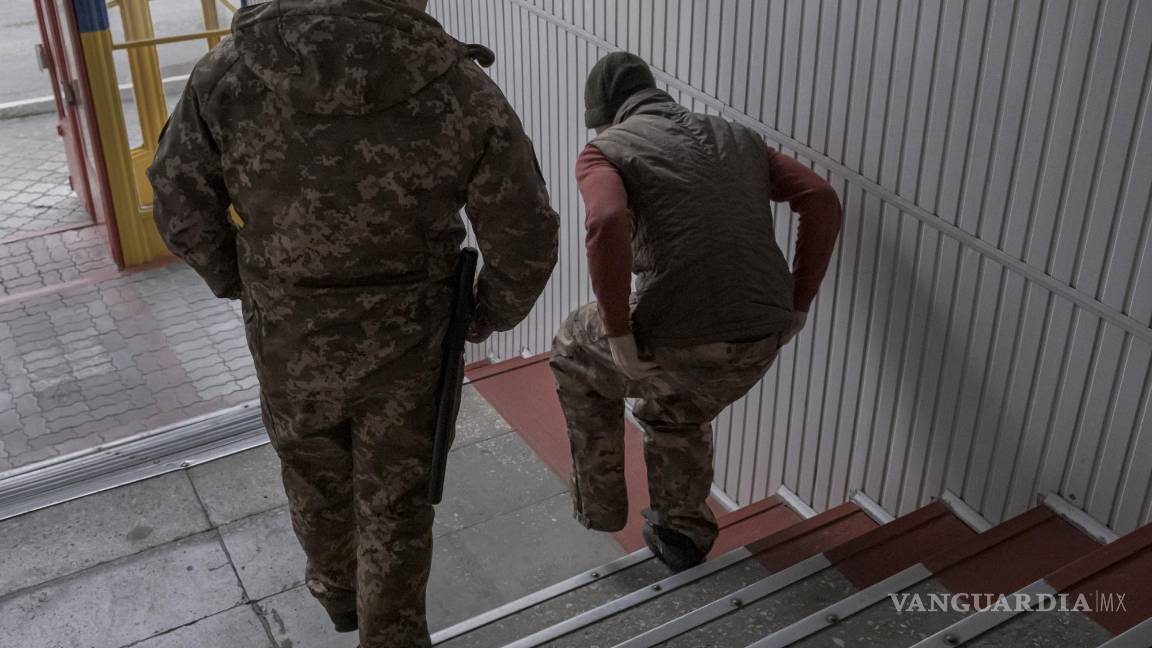 $!Un soldado de Wagner capturado es escoltado por un guardia ucraniano en una prisión en Dnipro.