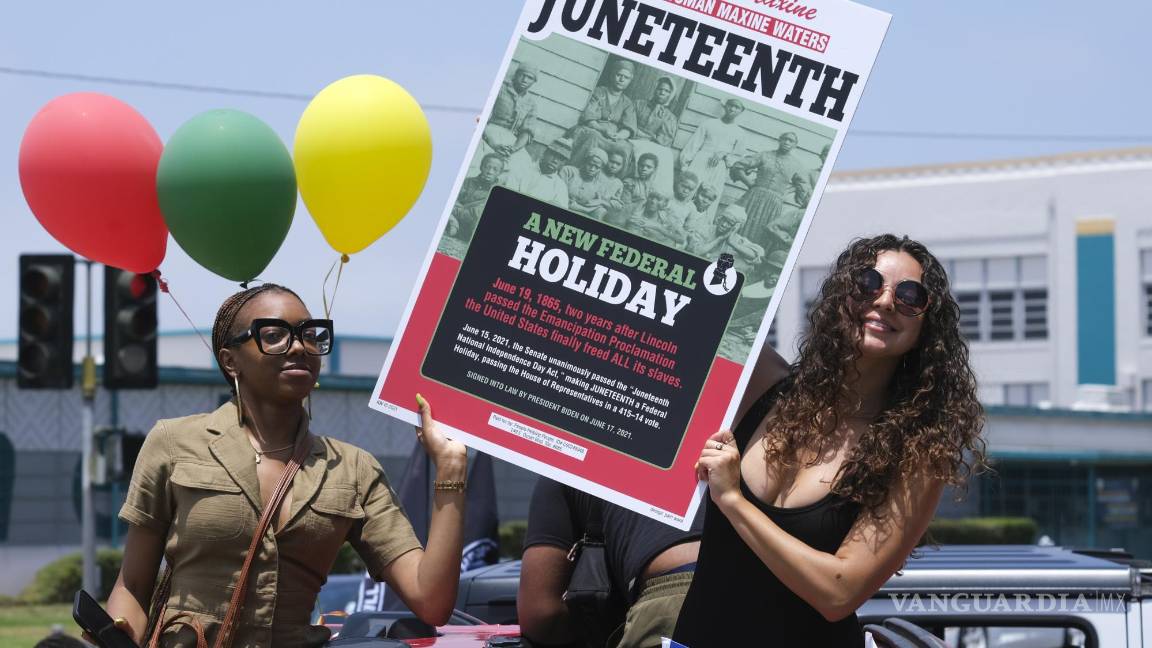 $!Las personas sostienen un cartel en su automóvil en un desfile de automóviles para conmemorar el 19 de junio, el 19 de junio de 2021, en Inglewood, California.