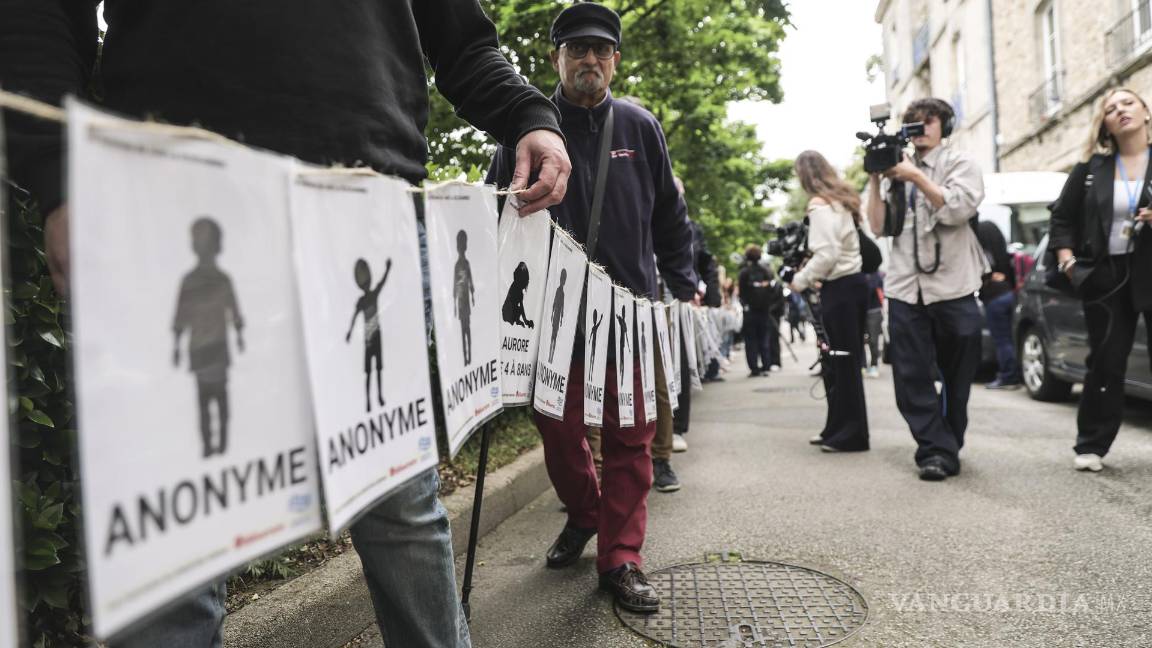 $!Personas, incluidas víctimas, portan pancartas que representan a las víctimas de Joel Le Scouarnec en el día del veredicto del juicio del cirujano francés en Vannes.