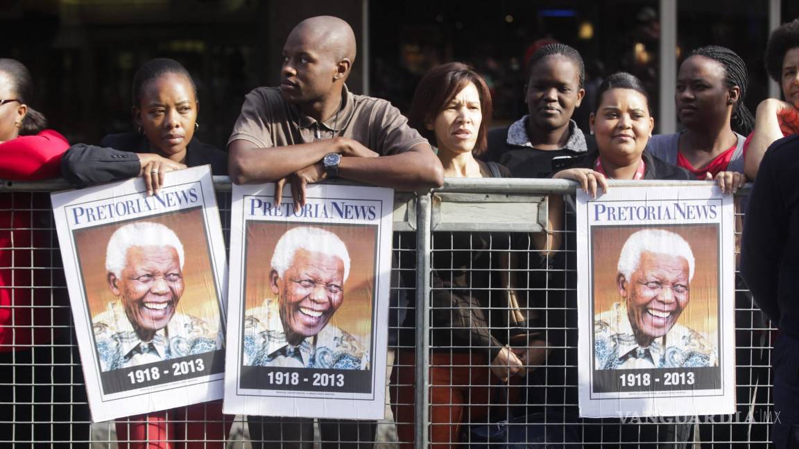 $!Sudafricanos sujetan carteles con la imagen de Madiba mientras aguardan la llegada del cortejo fúnebre con los restos mortales del expresidente sudafricano.