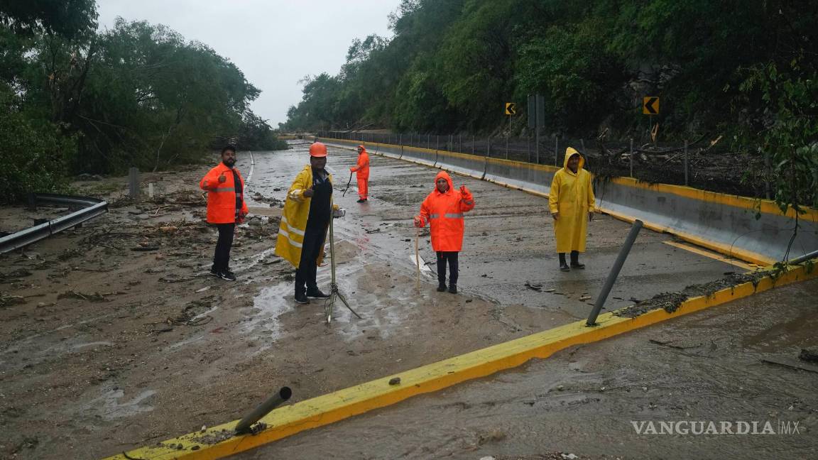 $!Trabajadores limpian una carretera bloqueada tras el paso del huracán Otis cerca de Acapulco, México.