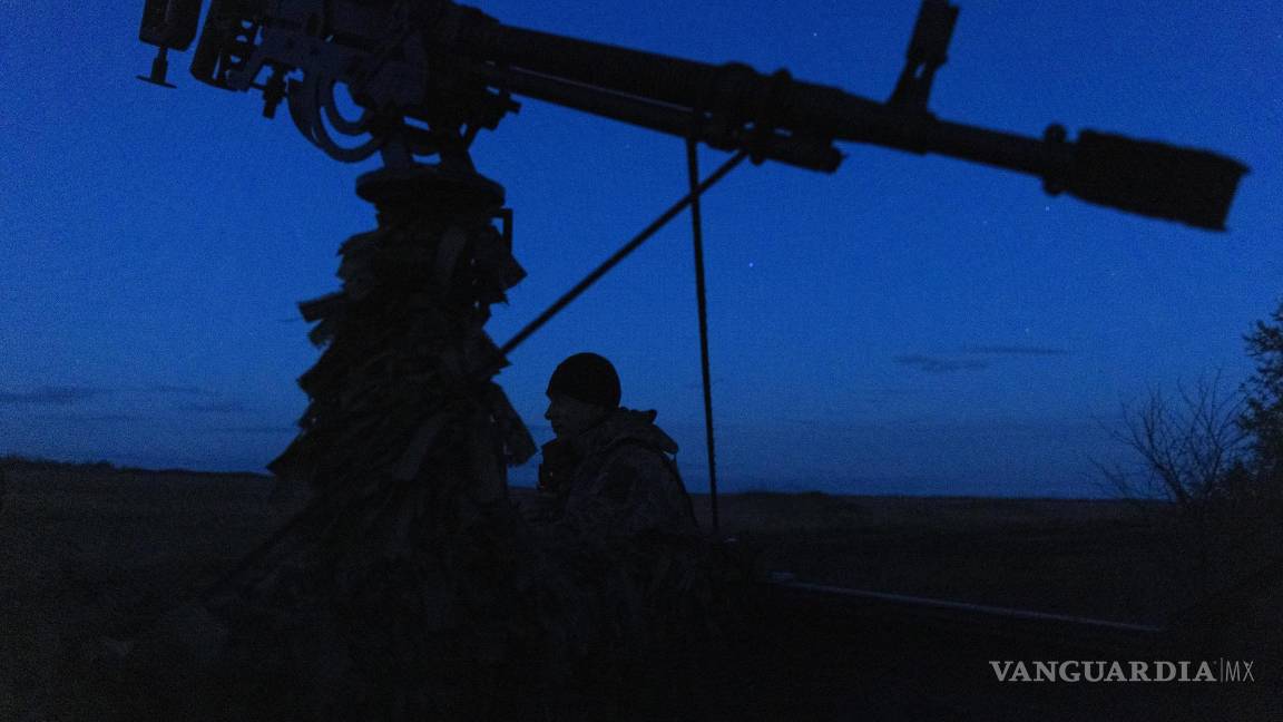 $!Un soldado parado cerca de un sistema de armas montado en una camioneta durante una patrulla nocturna, en busca de drones rusos.