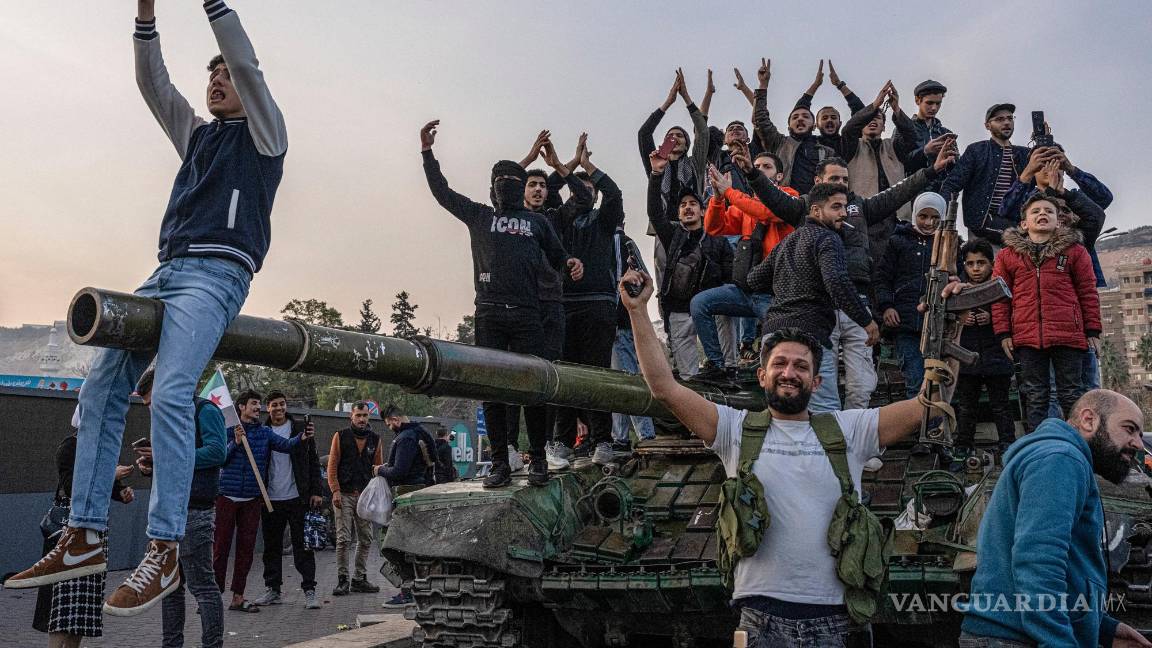 $!Los sirios se reúnen en un tanque en la plaza de los Omeyas en Damasco para celebrar el derrocamiento del presidente Bashar Assad.