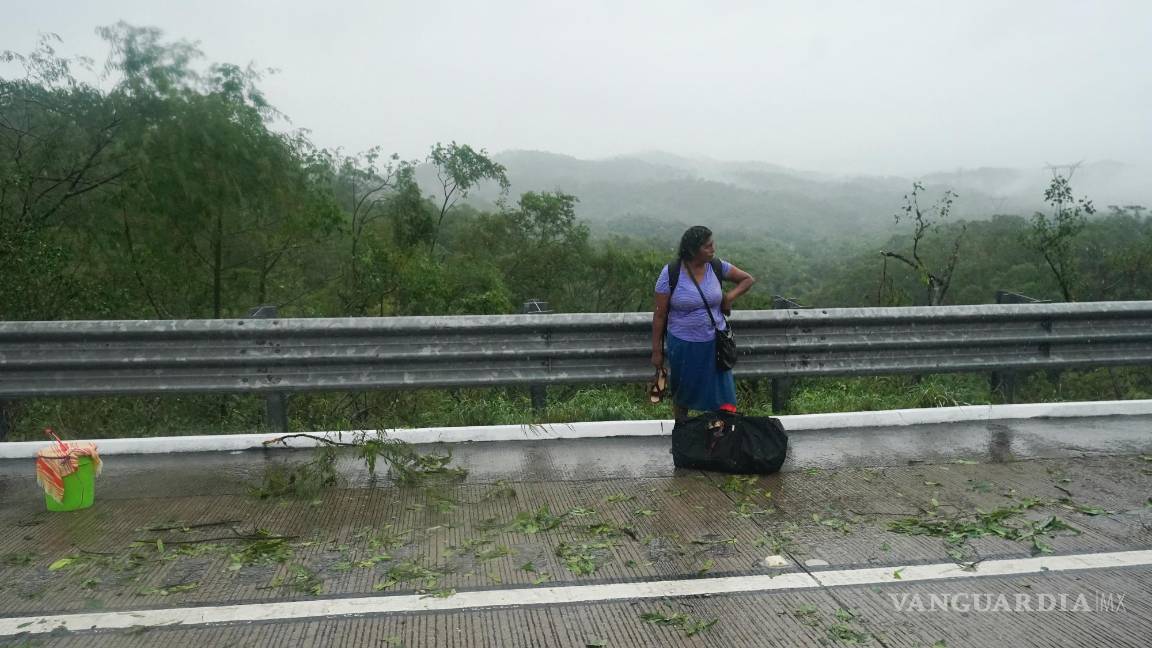 $!Una mujer que se bajó de un autobús parado en una carretera bloqueada por un deslizamiento de tierra provocado por el huracán Otis cerca de Acapulco, México.